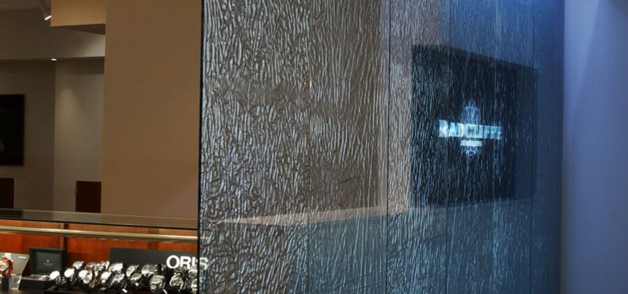 A banner showing the custom fabric laminated glass partition wall created for Radcliffe Jewelers by Archetype Glass