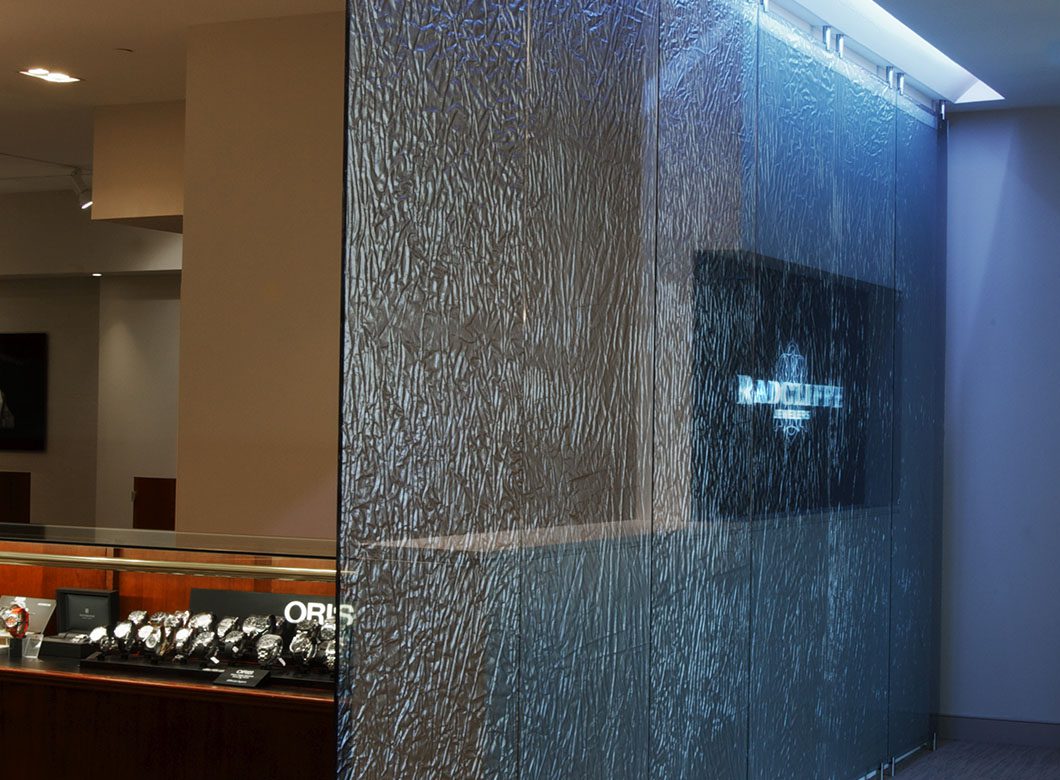 A detailed view of the fabric interlayer of the custom laminated glass partition wall for Radcliffe Jewelers, created by Archetype Glass